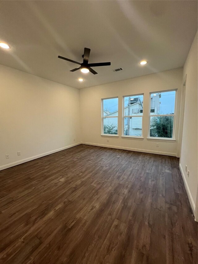 unfurnished room featuring ceiling fan, dark wood-type flooring, and a wealth of natural light