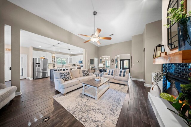 living room with a tile fireplace, ceiling fan, and a towering ceiling