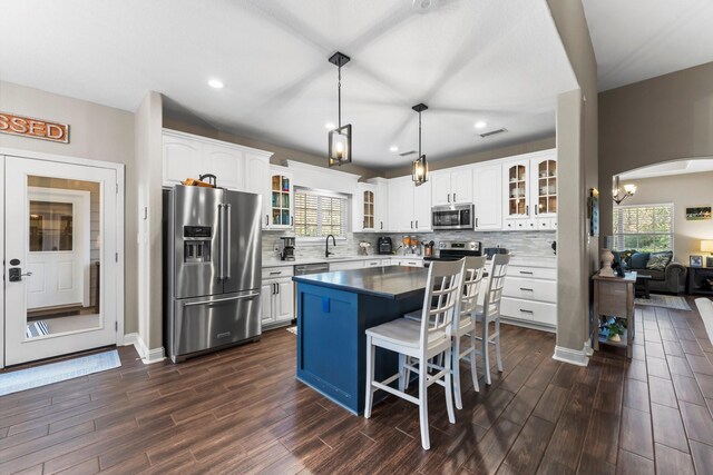 kitchen with white cabinetry, tasteful backsplash, pendant lighting, a kitchen island, and appliances with stainless steel finishes