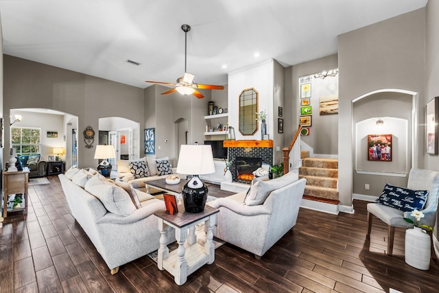 living room with a fireplace, a towering ceiling, and ceiling fan