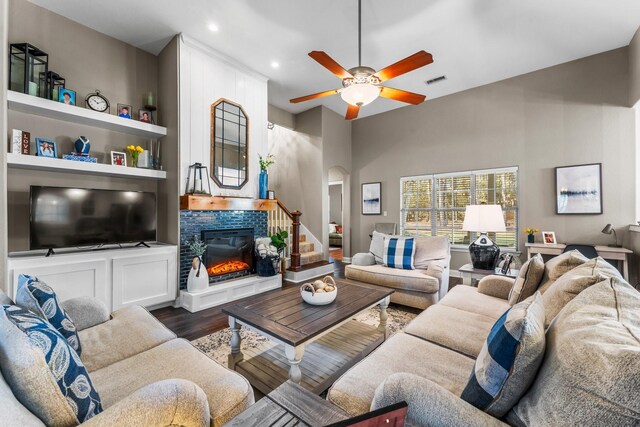 living room with built in shelves, ceiling fan, and dark hardwood / wood-style floors