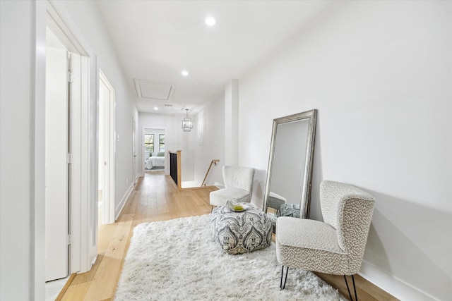 hallway with baseboards, light wood-style flooring, an upstairs landing, and recessed lighting