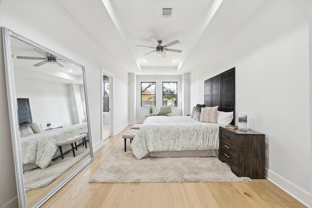 bedroom featuring a tray ceiling, recessed lighting, visible vents, light wood-style flooring, and baseboards