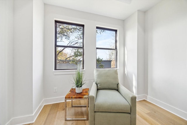 living area with light wood-type flooring and baseboards