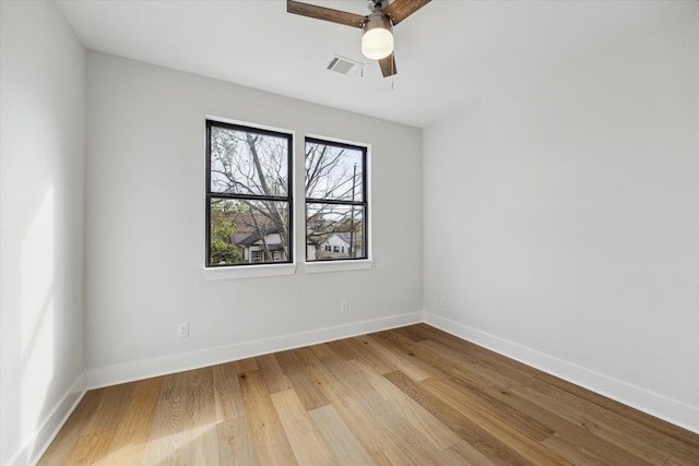 unfurnished room with ceiling fan, light wood-style flooring, visible vents, and baseboards