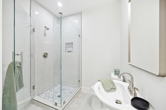 bathroom with baseboards, toilet, a shower stall, a sink, and recessed lighting