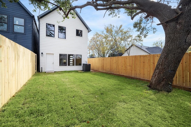 back of property featuring a fenced backyard, a yard, and central AC unit