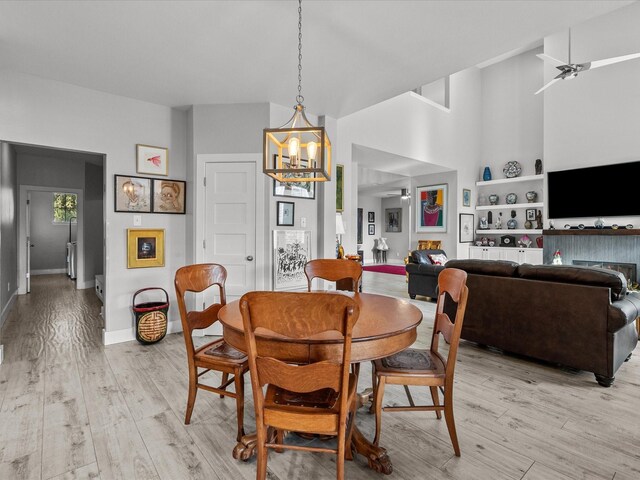 dining room with ceiling fan with notable chandelier and light wood-type flooring