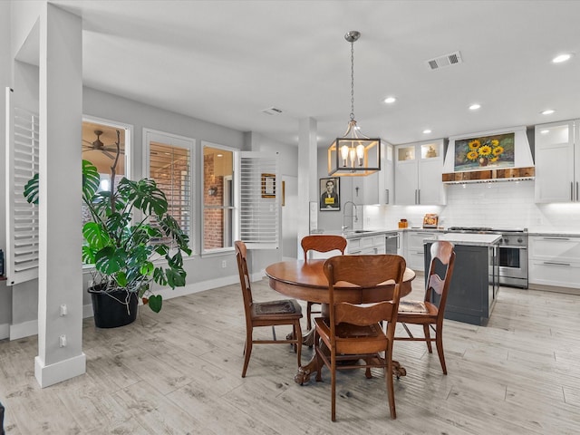 dining area featuring a notable chandelier, sink, and light hardwood / wood-style flooring