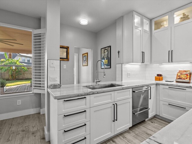 kitchen featuring white cabinets, light stone counters, and sink