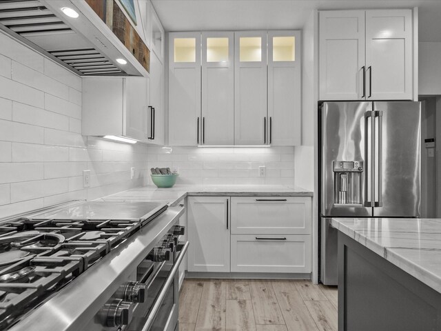 kitchen featuring ventilation hood, high end appliances, and white cabinetry