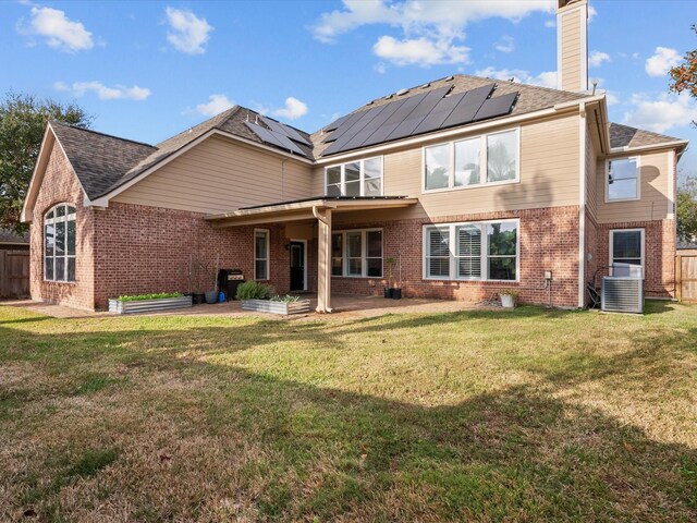 rear view of house featuring a lawn, cooling unit, a patio, and solar panels