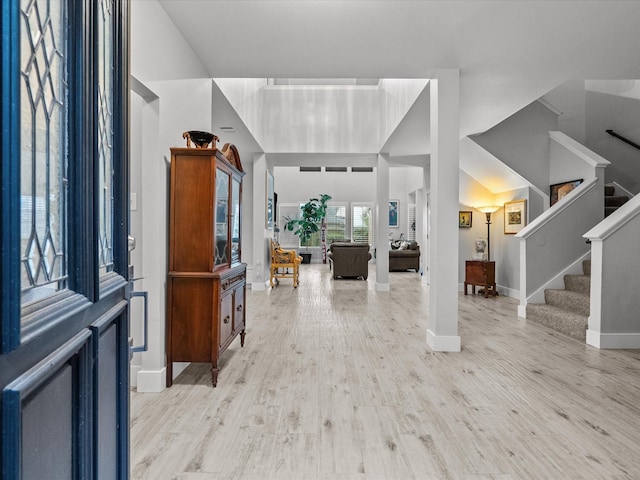 foyer entrance with light hardwood / wood-style flooring and a towering ceiling