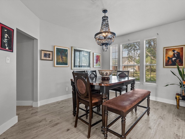 dining space with light wood-type flooring and a chandelier