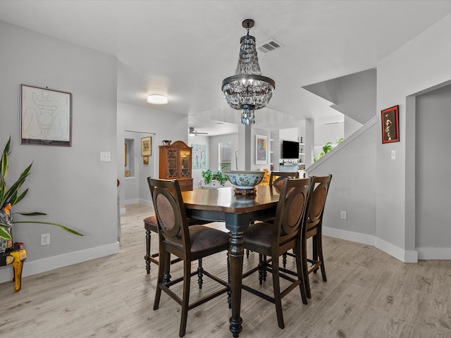 dining area with light hardwood / wood-style floors and ceiling fan with notable chandelier