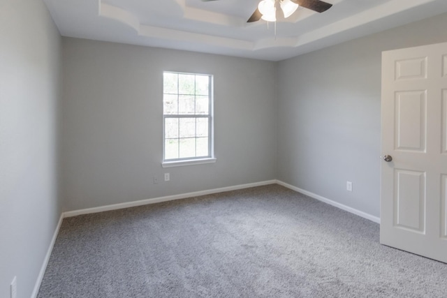 carpeted spare room featuring a tray ceiling and ceiling fan