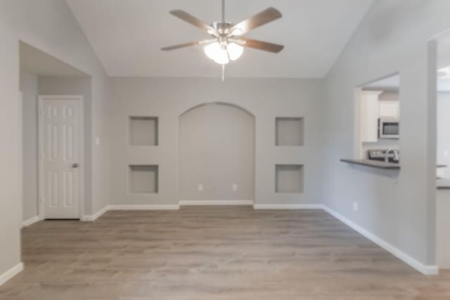 unfurnished living room with ceiling fan, lofted ceiling, and light wood-type flooring