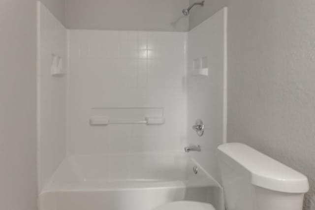 bathroom featuring toilet and tiled shower / bath