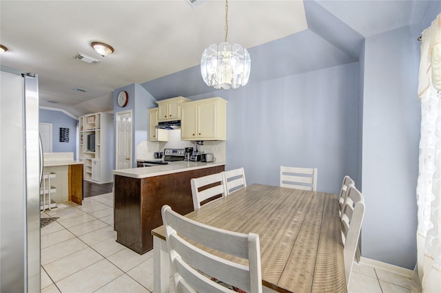 kitchen featuring pendant lighting, backsplash, cream cabinets, vaulted ceiling, and stainless steel appliances