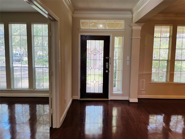 entryway with crown molding, ornate columns, and dark wood-type flooring