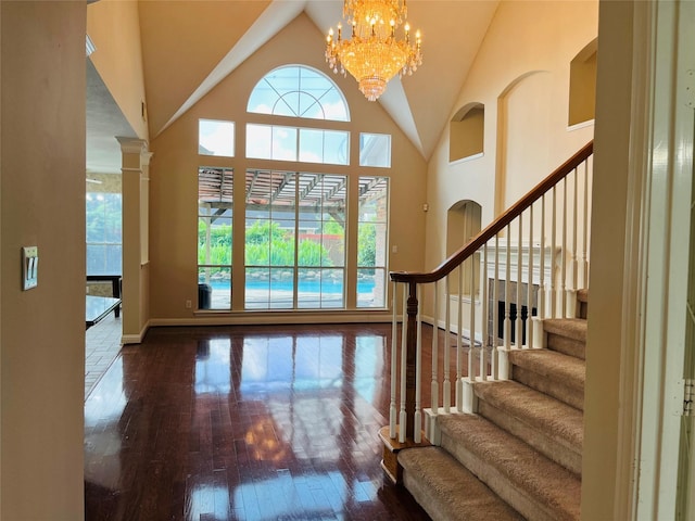 entrance foyer with high vaulted ceiling, wood-type flooring, and a notable chandelier