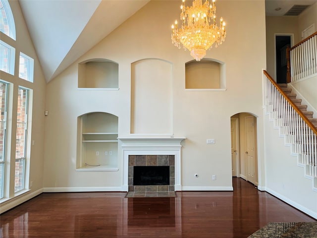 unfurnished living room featuring built in features, high vaulted ceiling, dark hardwood / wood-style floors, and a notable chandelier