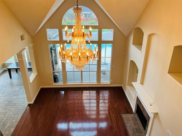 entrance foyer with dark hardwood / wood-style flooring, plenty of natural light, high vaulted ceiling, and an inviting chandelier