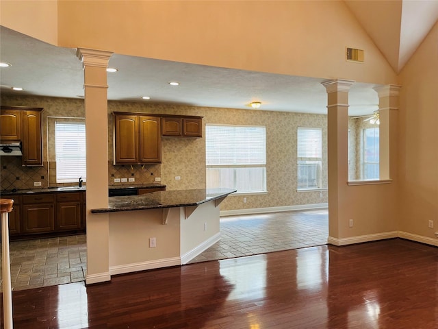 kitchen featuring a breakfast bar area, ceiling fan, dark hardwood / wood-style flooring, and dark stone counters