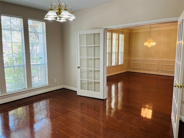 unfurnished dining area featuring crown molding, dark hardwood / wood-style flooring, and an inviting chandelier