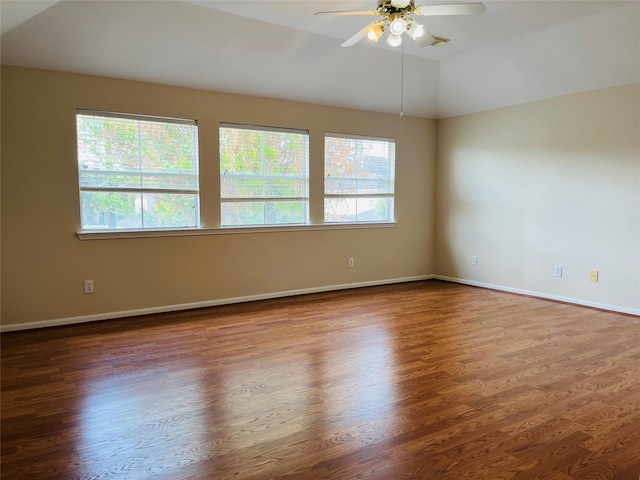 spare room featuring lofted ceiling, dark hardwood / wood-style flooring, and a healthy amount of sunlight