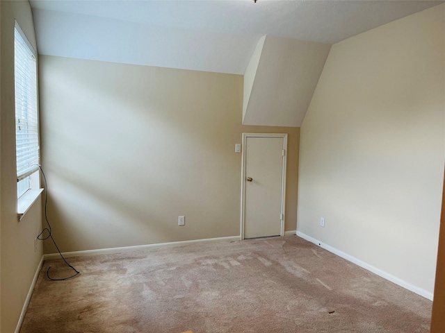 empty room with carpet floors and vaulted ceiling