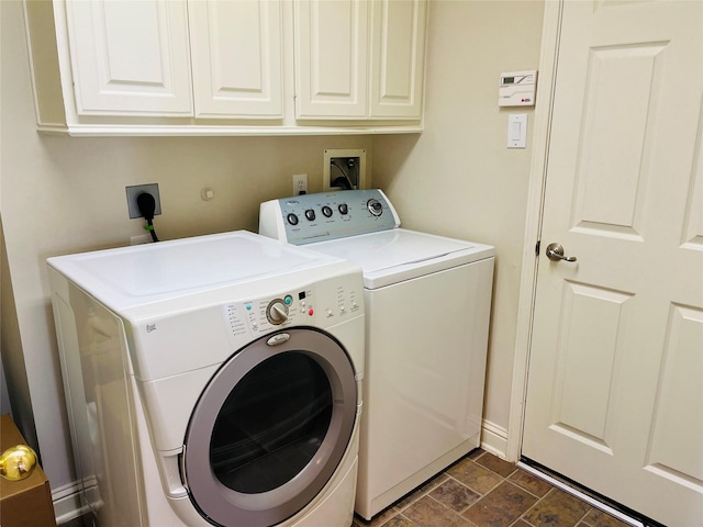 clothes washing area featuring cabinets and separate washer and dryer