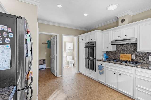 kitchen featuring light tile patterned floors, appliances with stainless steel finishes, white cabinetry, and dark stone counters