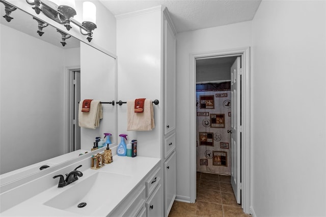 bathroom with a textured ceiling, tile patterned flooring, and vanity