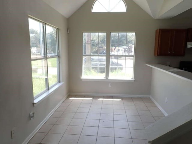 unfurnished dining area with light tile patterned floors and vaulted ceiling