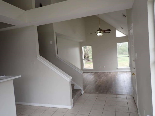 staircase featuring ceiling fan, tile patterned flooring, and high vaulted ceiling