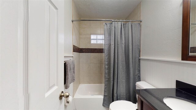 full bathroom with shower / bath combo, toilet, a textured ceiling, and vanity