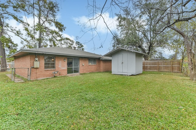 rear view of property featuring a lawn and a storage unit