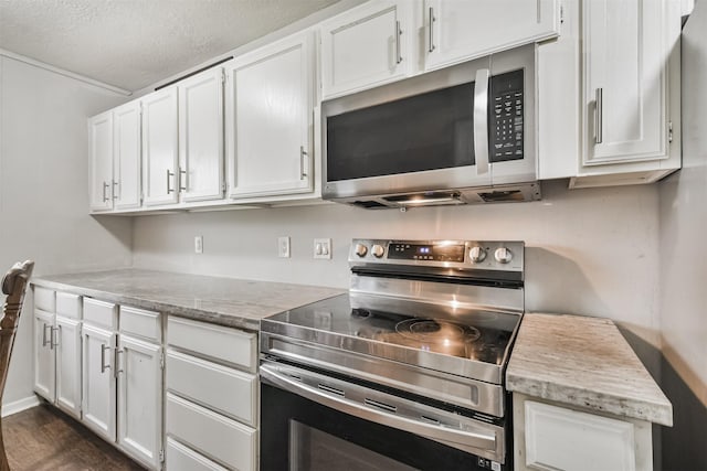 kitchen with white cabinets, appliances with stainless steel finishes, a textured ceiling, and dark hardwood / wood-style floors