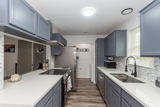 kitchen with sink, hardwood / wood-style floors, extractor fan, decorative backsplash, and black appliances