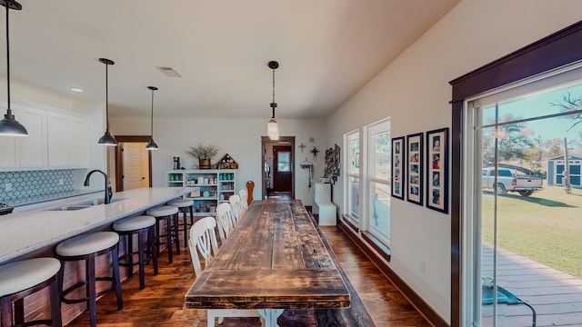 dining area featuring sink, dark wood-type flooring, and lofted ceiling