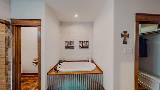 bathroom with a bathing tub, toilet, and wood-type flooring