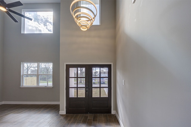 entrance foyer with dark wood-type flooring, french doors, a towering ceiling, and ceiling fan with notable chandelier