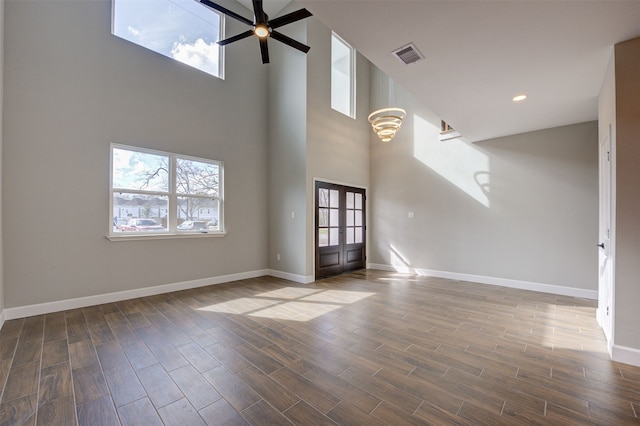 unfurnished living room with ceiling fan, french doors, and a towering ceiling