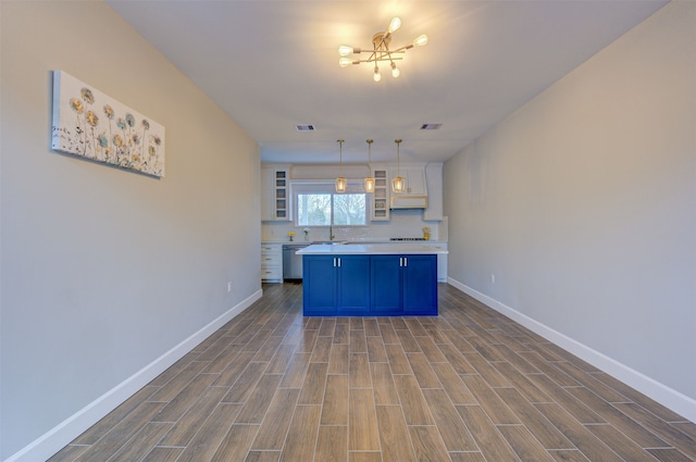 kitchen featuring white cabinetry, tasteful backsplash, dishwasher, blue cabinets, and hanging light fixtures