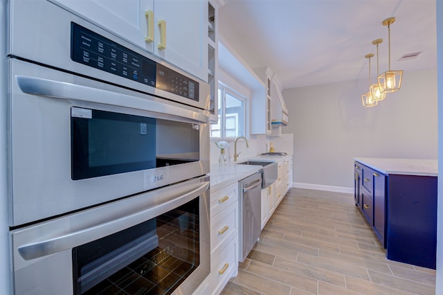 kitchen featuring decorative light fixtures, sink, blue cabinetry, stainless steel appliances, and white cabinets