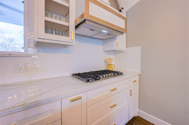 kitchen with stainless steel gas stovetop, white cabinetry, backsplash, and light stone countertops