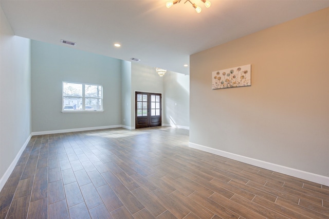 empty room featuring french doors and a notable chandelier