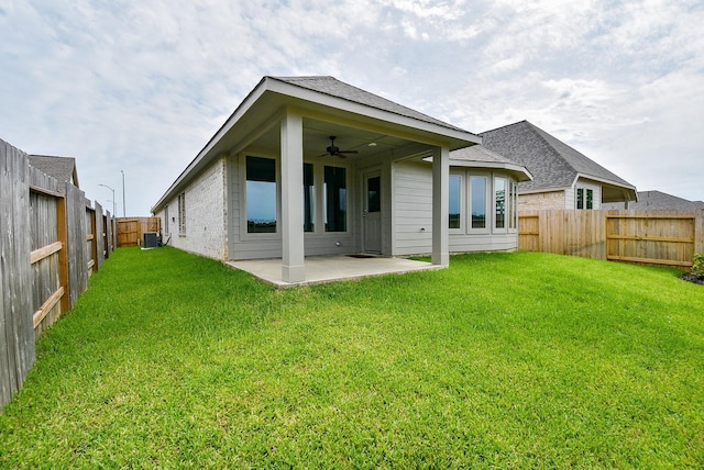 rear view of property featuring a lawn, ceiling fan, cooling unit, and a patio