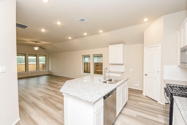 kitchen with a kitchen island with sink, white cabinets, sink, vaulted ceiling, and stainless steel appliances